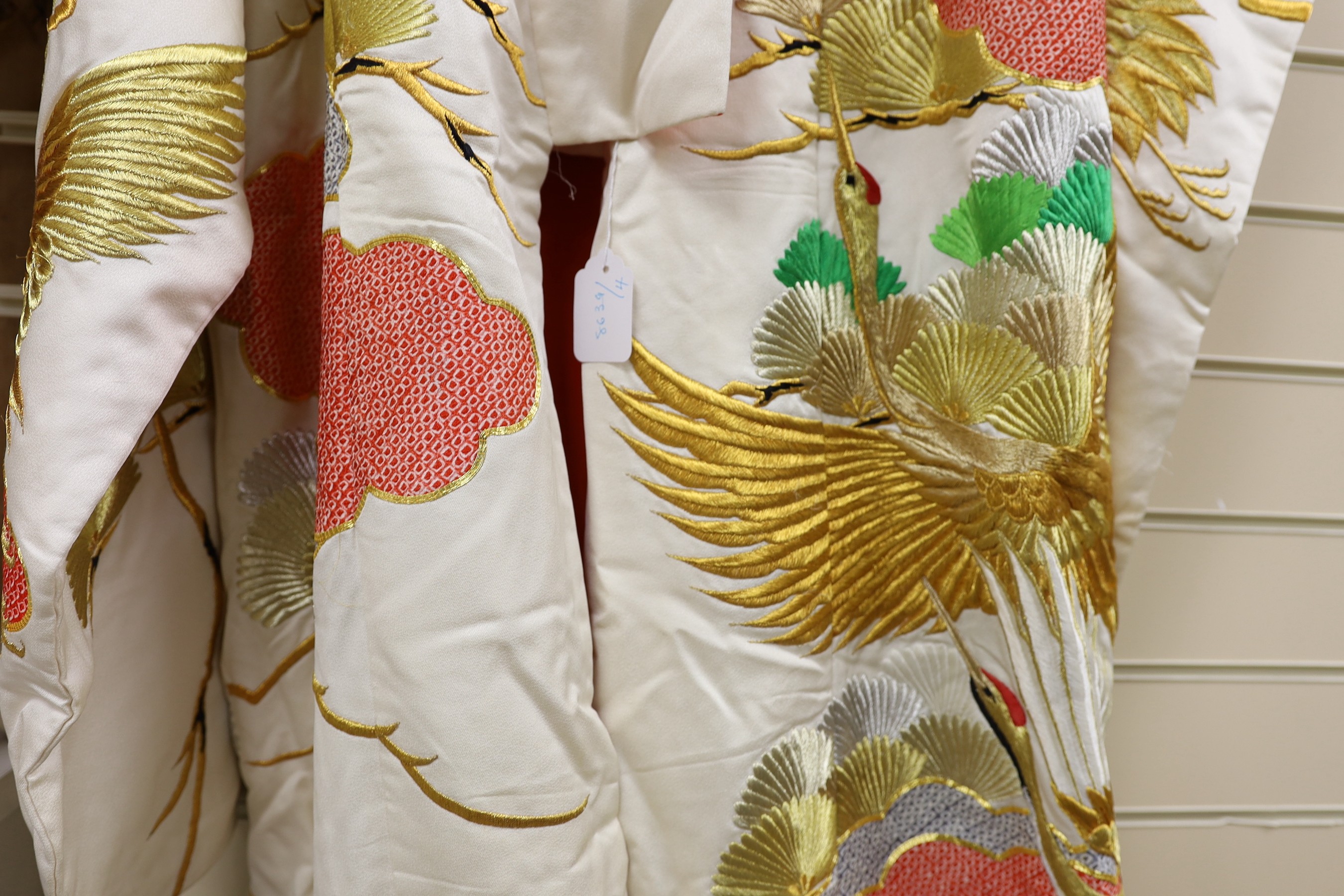 A Japanese cream ground ceremonial kimono, embroidered with coloured silks and metallic embroidery, in an all over design, with flame red silk lining